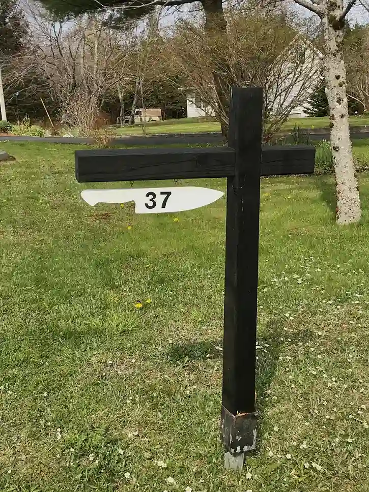 37 Melody Drive - Brookside A black wooden street sign post with a white knife shaped plate hanging underneath with the number 37 on it.